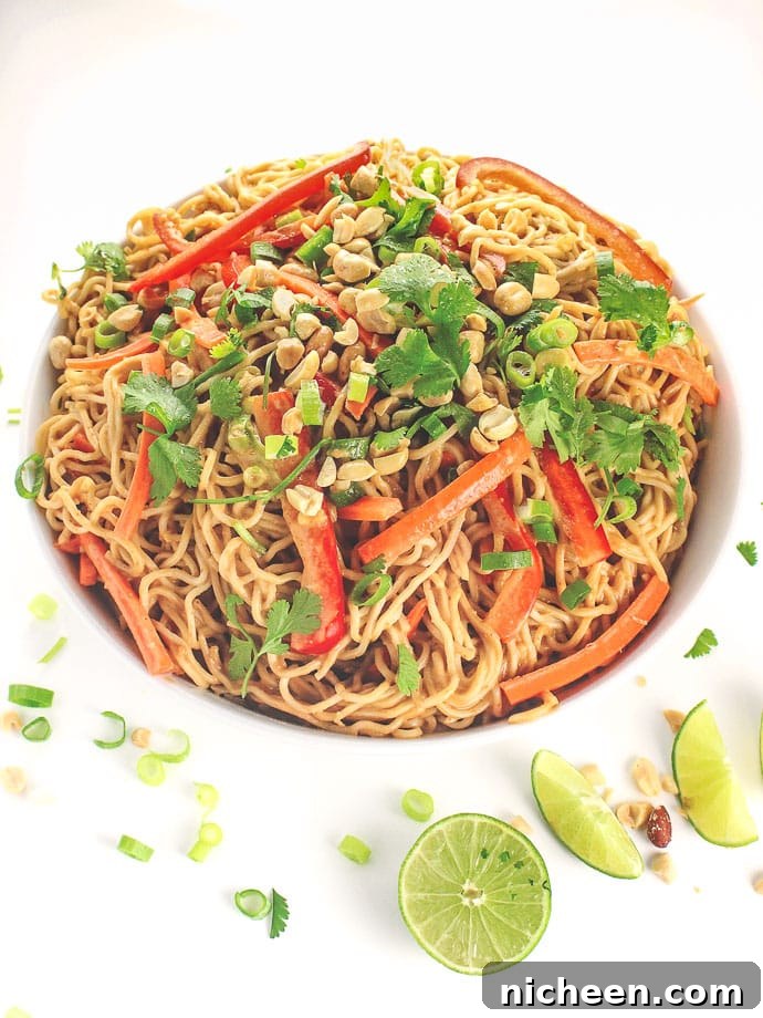 Peanut noodles in a bowl with lemon slices placed around the bowl. 