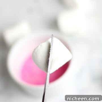 Marshmallow Bunny Ears Recipe for Cute Easter Treats 8 Marshmallow being cut in half for bunny ears with pink sprinkles in the background.