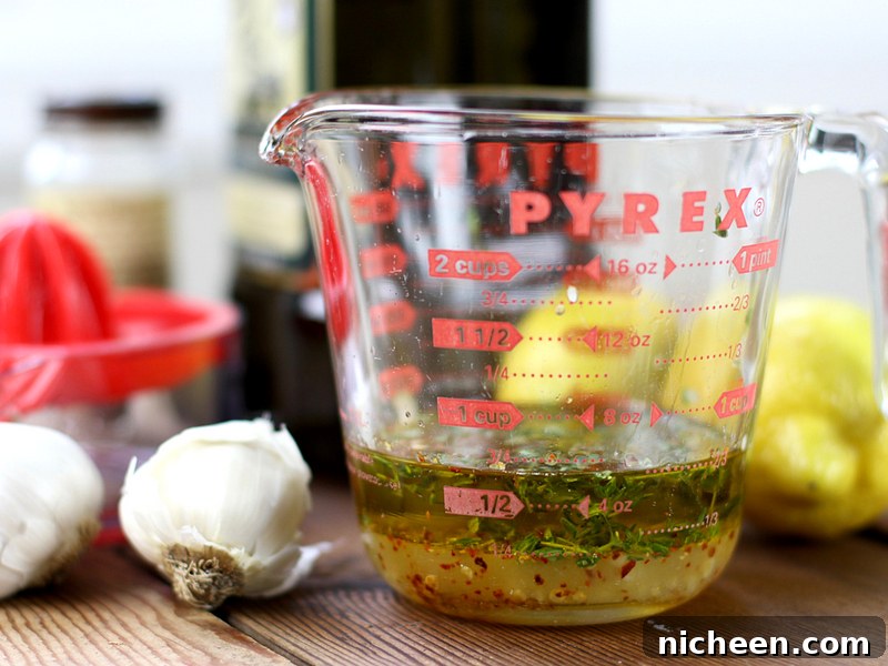 Oven-Baked Lemon Chicken Recipe: Crispy, Tender 4 measuring cup with olive oil with a garlic clove next to it.