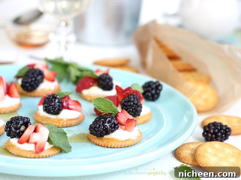 Plate full of crackers topped with berries and cream.
