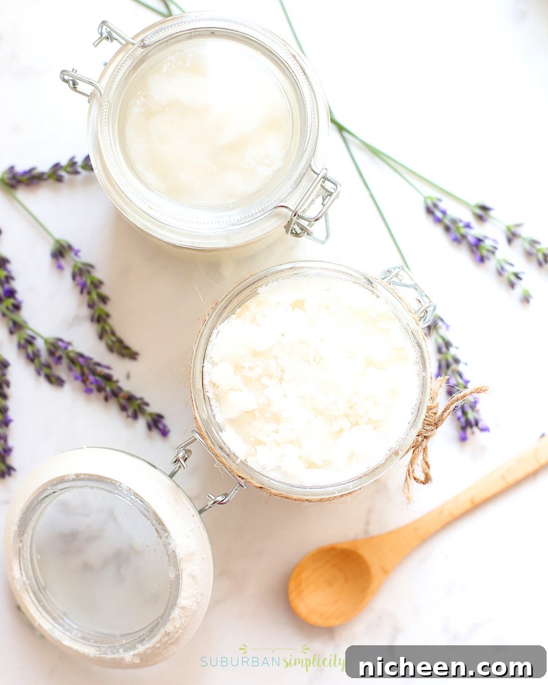 two jars of homemade body scrub with a wooden spoon next to them.
