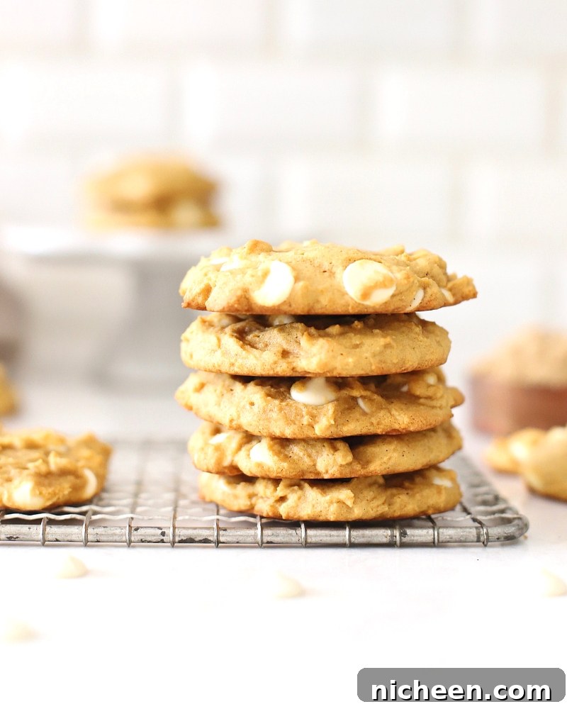White Chocolate Chip Pumpkin Spice Cookies Recipe 6 Pumpkin spice cookies stacked on a cooling rack.