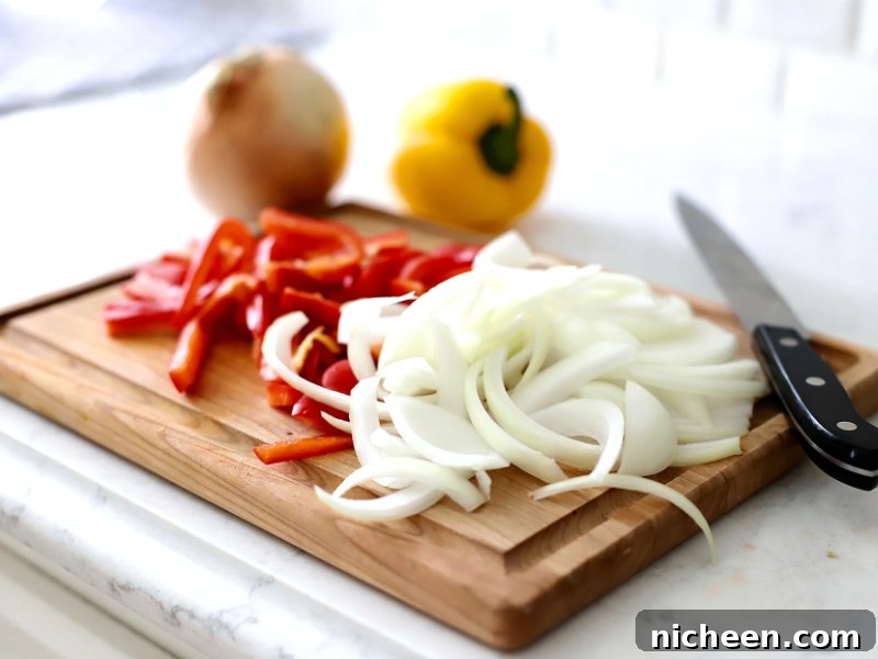 Homemade Philly Cheesesteak Burger Recipe 4 Sliced Peppers and onions on a cutting board.
