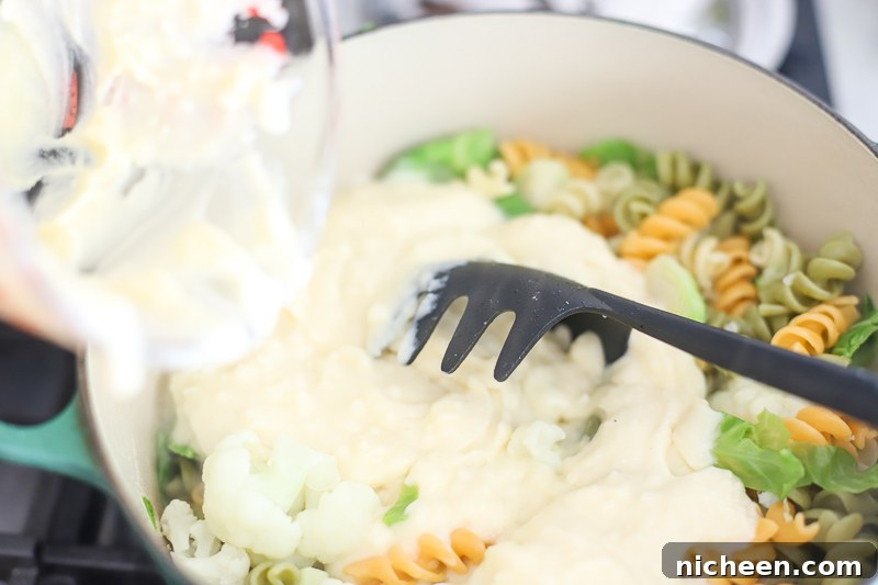 Cheese sauce being poured over a pot of macaroni