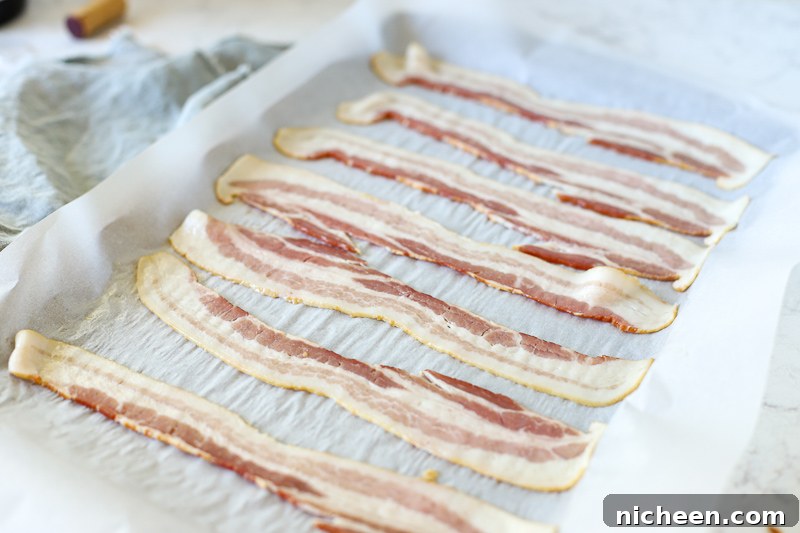How to Cook Bacon in the Oven for Crispy, Evenly Cooked Strips 5 raw bacon on a baking sheet.