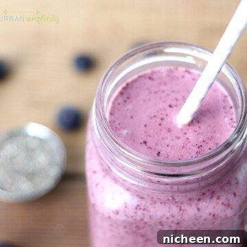 Blueberry Smoothie to Boost Your Metabolism 5 Metabolism Boosting Blueberry Smoothie in a mason jar with a straw. Chia seeds are scattered in the background.