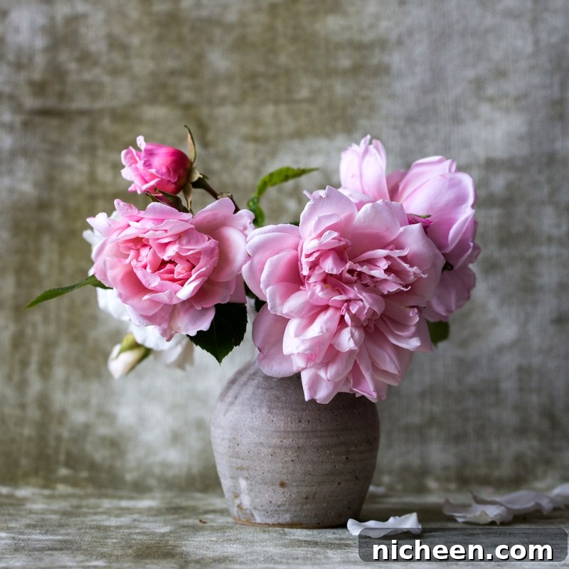 10 Practical Ways to Stop Feeling So Busy 5 Pink flowers in a vase with a gray backdrop.
