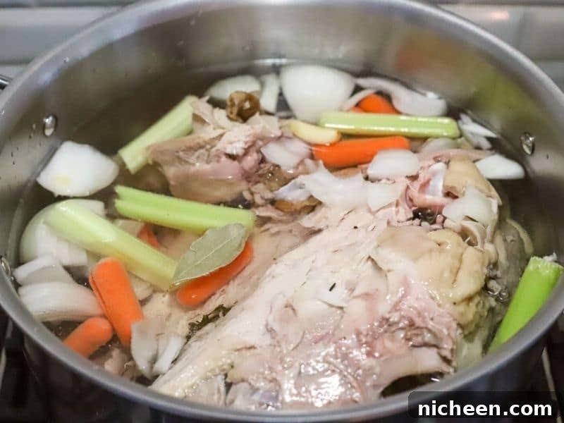 carrots, celery, onions and a turkey carcass in a pot
