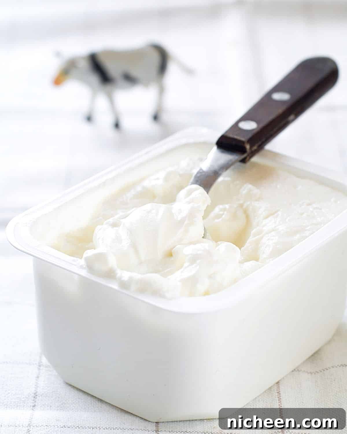 cream cheese in a container with a knife.