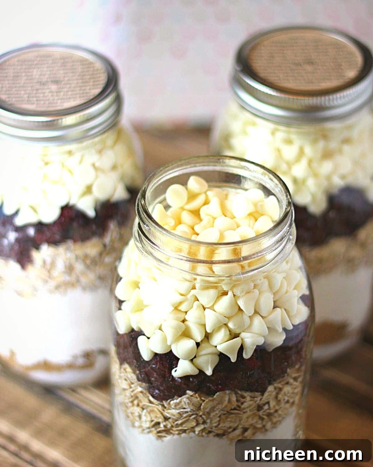 Cranberry White Chocolate Oatmeal Cookie Mix in a Jar 3 White chocolate chips layered on top of cranberries and oatmeal in a jar.
