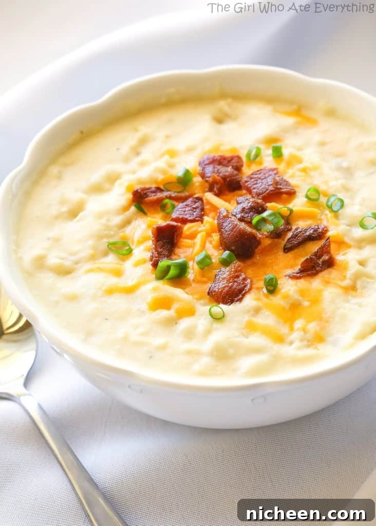 Potato soup in a bowl topped with bacon and chives.